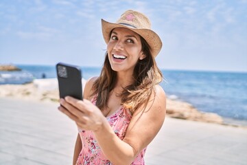 Brunette woman enjoying a summer day at the beach using smartphone