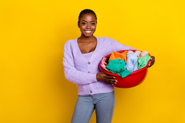 Photo of positive person hands hold dirty clothes laundry basket isolated on yellow color background