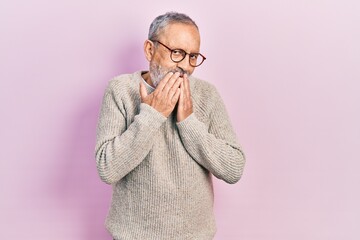 Handsome senior man with beard wearing casual sweater and glasses laughing and embarrassed giggle covering mouth with hands, gossip and scandal concept