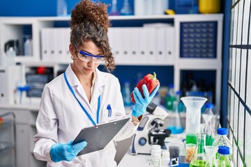 Young hispanic woman scientist smiling confident measuring liquid at laboratory