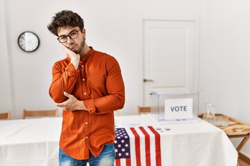Hispanic man standing by election room thinking looking tired and bored with depression problems...