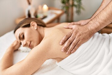 Woman smiling happy reciving back massage at beauty center.