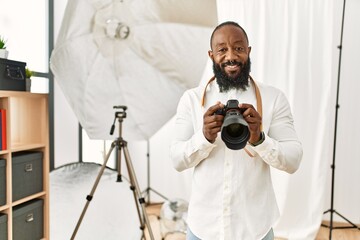 African american photographer man working at photography studio with a happy and cool smile on face. lucky person.