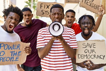 Group of young african american activists protesting holding banner and using megaphone at the city.