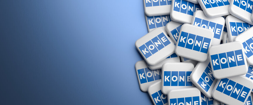 Logos of the Finnish elevator engineering and service company KONE on a heap on a table. Copy space. Web banner format.