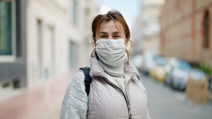 Middle age hispanic woman wearing medical mask at street