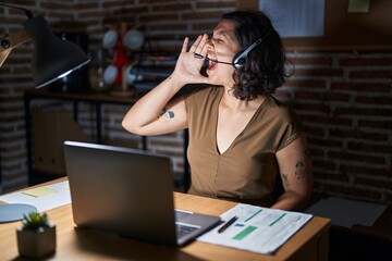 Young hispanic woman working at the office at night shouting and screaming loud to side with hand on mouth. communication concept.