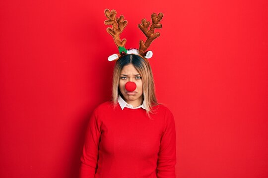 Beautiful Hispanic Woman Wearing Deer Christmas Hat And Red Nose Skeptic And Nervous, Frowning Upset Because Of Problem. Negative Person.