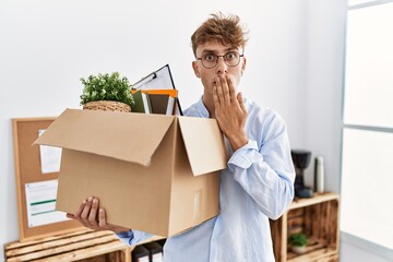 Young caucasian man holding business box covering mouth with hand, shocked and afraid for mistake. surprised expression