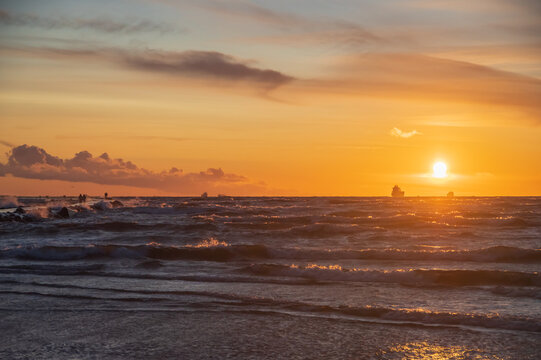 Soft focus image of of sunset in orange sky over ships leaving the harbor on windy sunny evening 