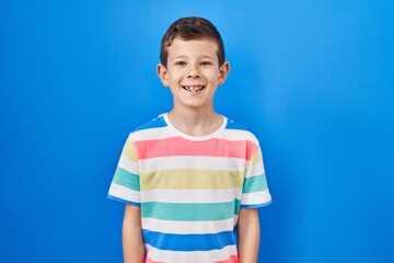 Young caucasian kid standing over blue background with a happy and cool smile on face. lucky person.
