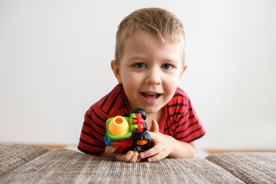 cute little boy of three with a toy in his hands at home by the couch.