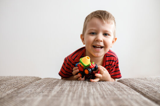 cute little boy of three with a toy in his hands at home by the couch.