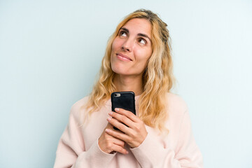Young caucasian woman holding mobile phone isolated on blue background