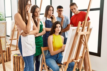 Group of people with serious expression looking draw of partner at art studio.