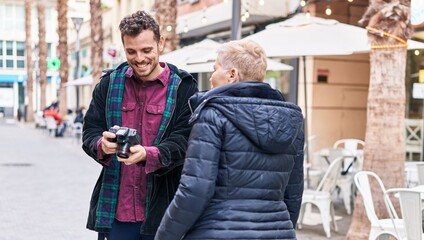 Mother and son smiling confident using professional camera at street