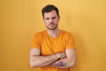 Young hispanic man standing over yellow background skeptic and nervous, disapproving expression on...