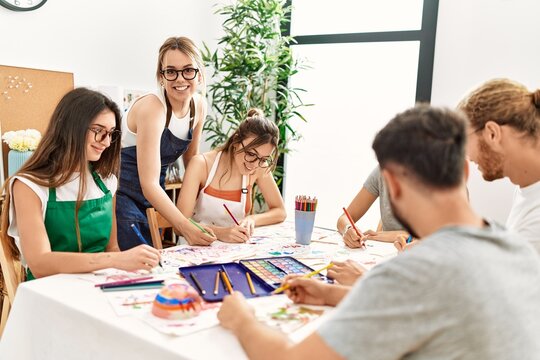Group of young paint students smiling happy and drawing sitting on the table at art studio.