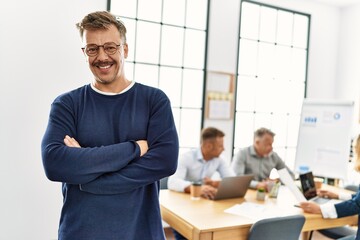 Middle age caucasian businessman smiling happy standing with arms crossed gesture at the office during business meeting.