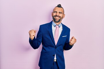 Young hispanic man wearing business suit and tie very happy and excited doing winner gesture with arms raised, smiling and screaming for success. celebration concept.