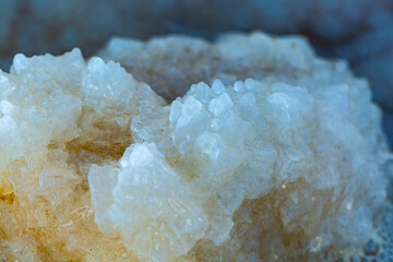 Blurred background of salts crystals from the Dead Sea. Selective focus, shallow depth of field. Background made of salt, large cubes. Macro of white crystals of rock sea salt. Crystallised sea-salt