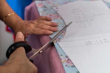 Latin American seamstress takes measurements with patterns in her workshop
