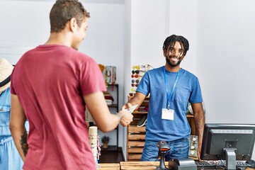 Obraz premium Two men shopkeeper and customer paying purchase with dollars at clothing store