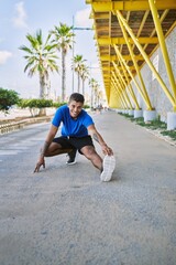 Fototapeta na wymiar Young hispanic man stretching leg muscles outdoors