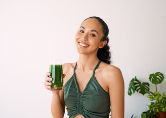 A beautiful multi-ethnic woman smiles with green juice - spinach, kale, vitamans