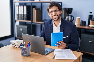 Young hispanic man business worker using laptop and touchpad working at office