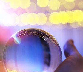 Crystal Ball on the floor with bokeh, lights behind. Glass ball with colorful bokeh light, celebration concept.
