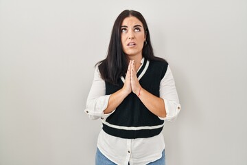Young hispanic woman standing over isolated background begging and praying with hands together with hope expression on face very emotional and worried. begging.