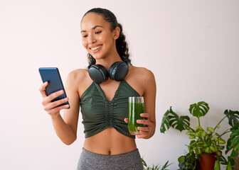 A young multi-ethnic woman tracks yoga session on fitness app with green juice