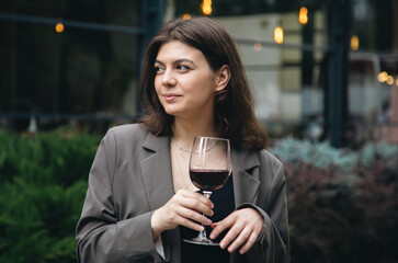 A young woman with a glass of wine outside near a restaurant.