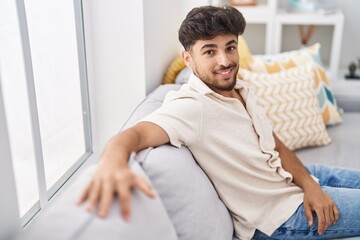 Fototapeta na wymiar Young arab man smiling confident sitting on sofa at home