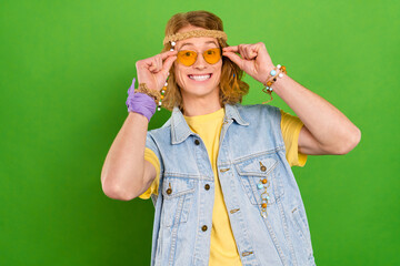 Portrait of cheerful good mood positive young man love hippie culture isolated on green color...