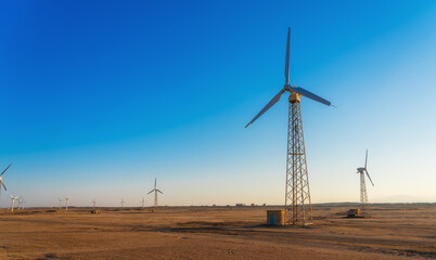 Wind power plants in desert at sunset