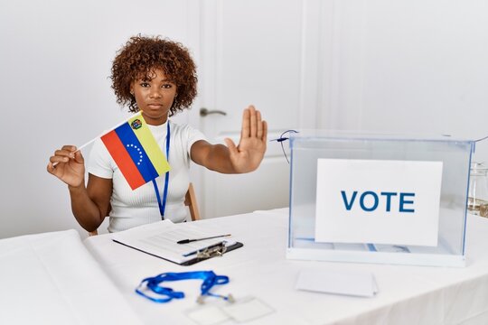 Young african american woman at political campaign election holding venezuela flag with open hand doing stop sign with serious and confident expression, defense gesture