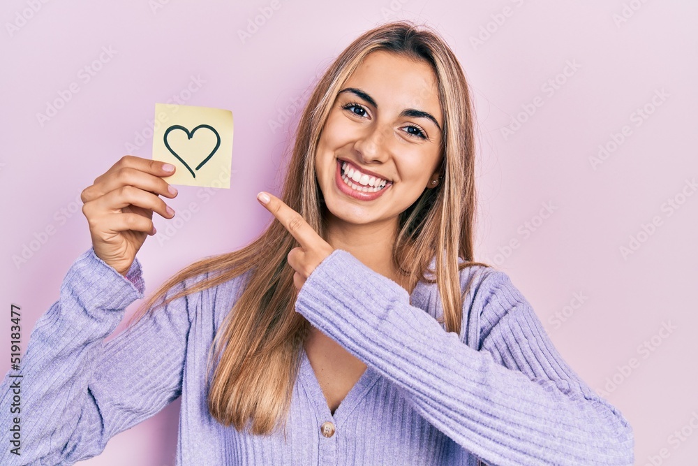 Poster beautiful hispanic woman holding heart reminder smiling happy pointing with hand and finger