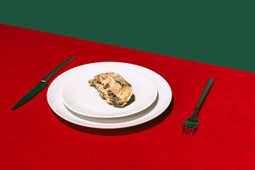 Plate of delicious oyster on red tablecloth isolated over green background. Traditional French...