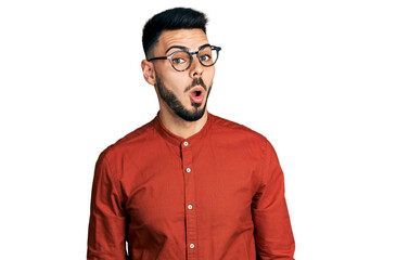 Obraz premium Young hispanic man with beard wearing business shirt and glasses afraid and shocked with surprise expression, fear and excited face.