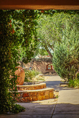 Fototapeta premium Rustic Santa Fe courtyard with fountain framed by adobe doorway with vines
