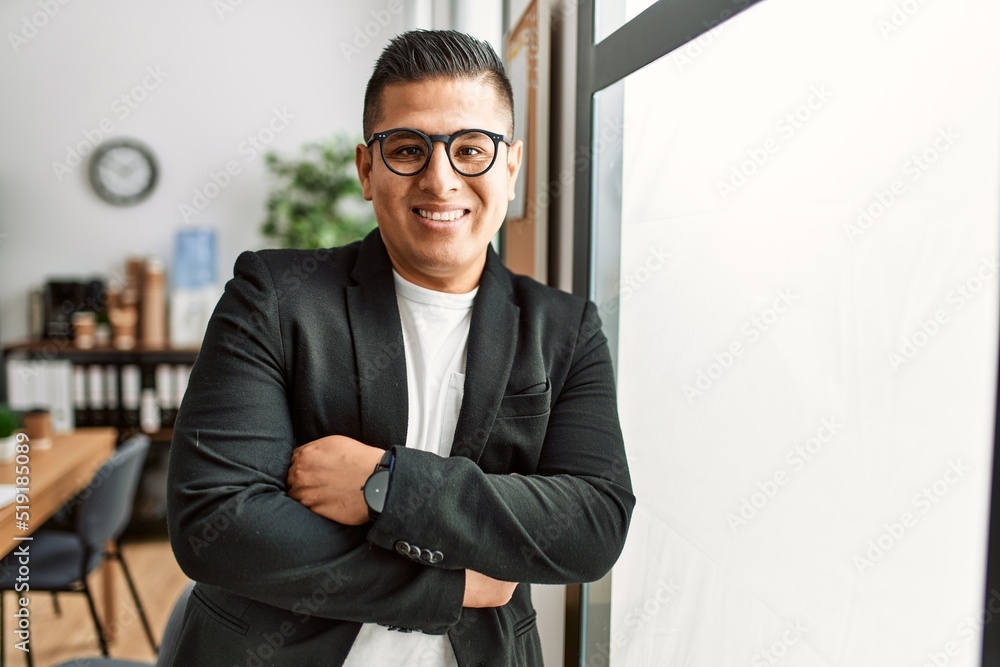 Sticker young latin businessman smiling happy standing with arms crossed gesture at the office.