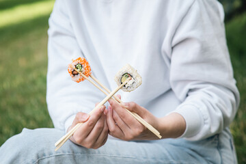 Close-up, woman eating sushi in summer in the park.