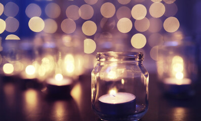 Background with candles in glass vessels. Candles burn in a dark place. Rest in peace.