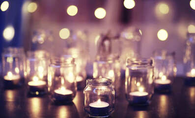 Background with candles in glass vessels. Candles burn in a dark place. Rest in peace.