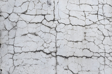 Closeup of badly fixed building facade wall covered with cracks in stucco and paint.