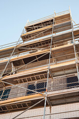Scaffolding on the faсade of the building under construction. A vertical image.