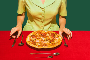 Delicious, fresh baked italian pizza with ham and sausage on red tablecloth isolated on green...