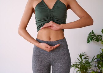 Cropped shot of a young multi-ethnic woman's stomach cupped by her hands - Powered by Adobe